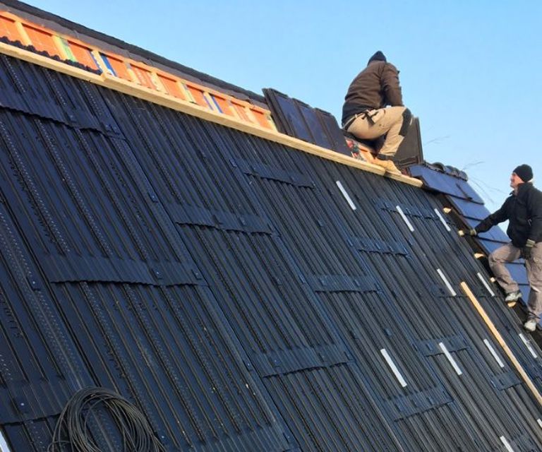Projectfoto van dakdekkers die solar panelen aan het monteren zijn op BEWI IsoBouw dakplaten. 