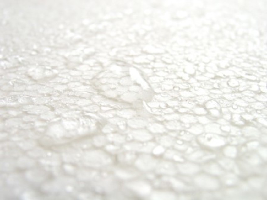Close-up foto van een stuk wit EPS isolatiemateriaal met daarop waterdruppels die niet intrekken. 