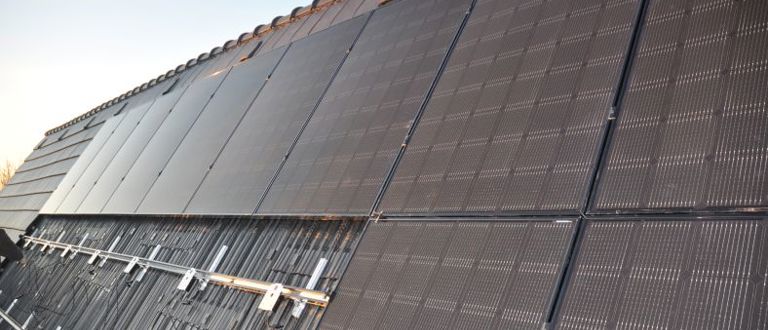 Close-up van de daknok die vol ligt met solar modules, zonnepanelen en dakpannen.