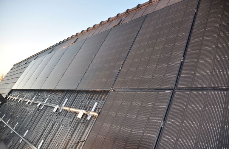 Close-up van de daknok die vol ligt met solar modules, zonnepanelen en dakpannen.