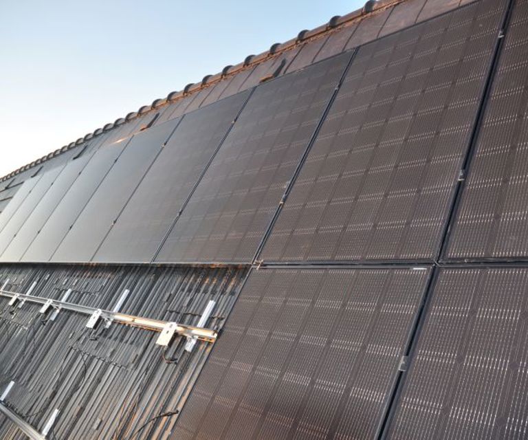 Close-up van de daknok die vol ligt met solar modules, zonnepanelen en dakpannen.
