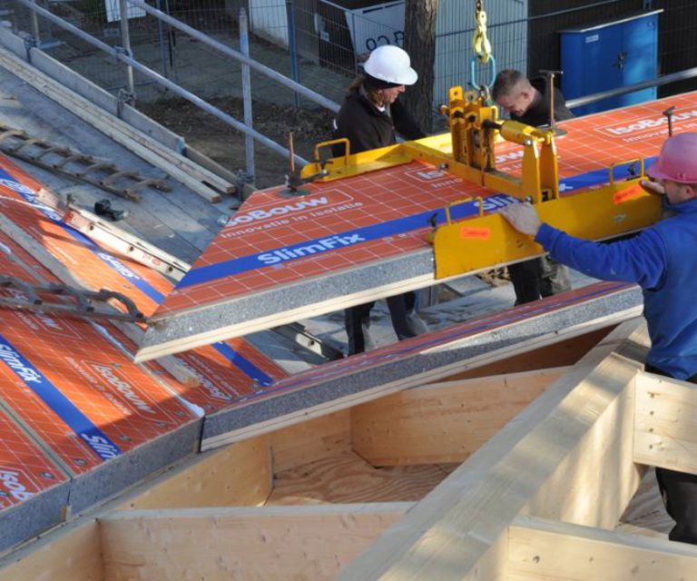 Projectfoto van dakdekkers die een SlimFix Flex paselement plaatsen d.m.v. een hijsklem.