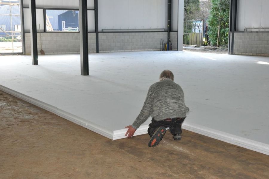 Projectfoto van een verwerker die een vloer met Eco Klik-vloerplaten legt in een fabriekshal. 