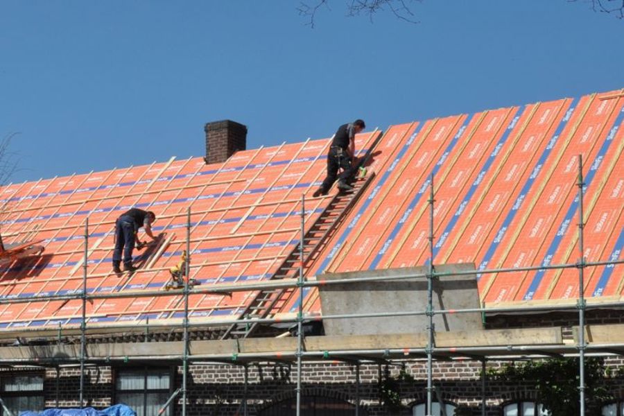 Projectfoto van personen die op het dak de BEWI IsoBouw dakelementen aan het bevestigen zijn. 