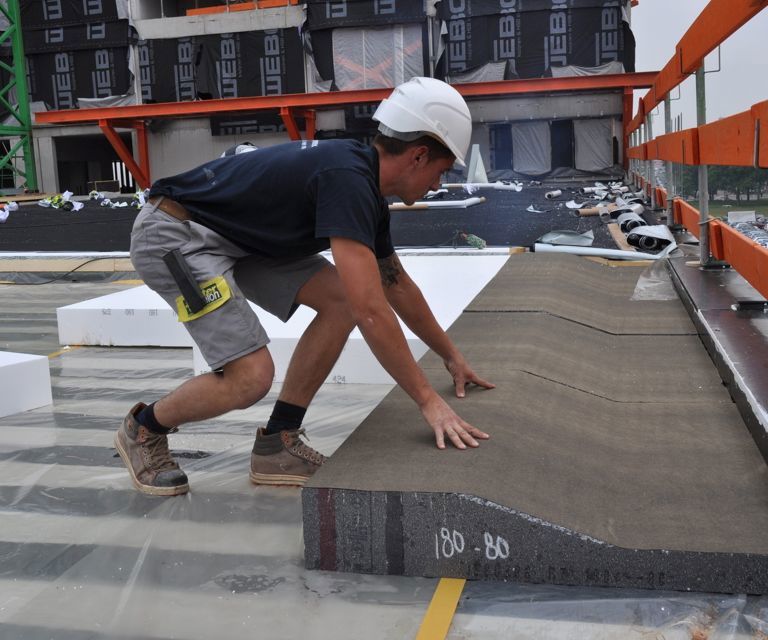 Projectfoto van een verwerker die een RenoTop HR afschotplaat tegen de dakrand legt. 