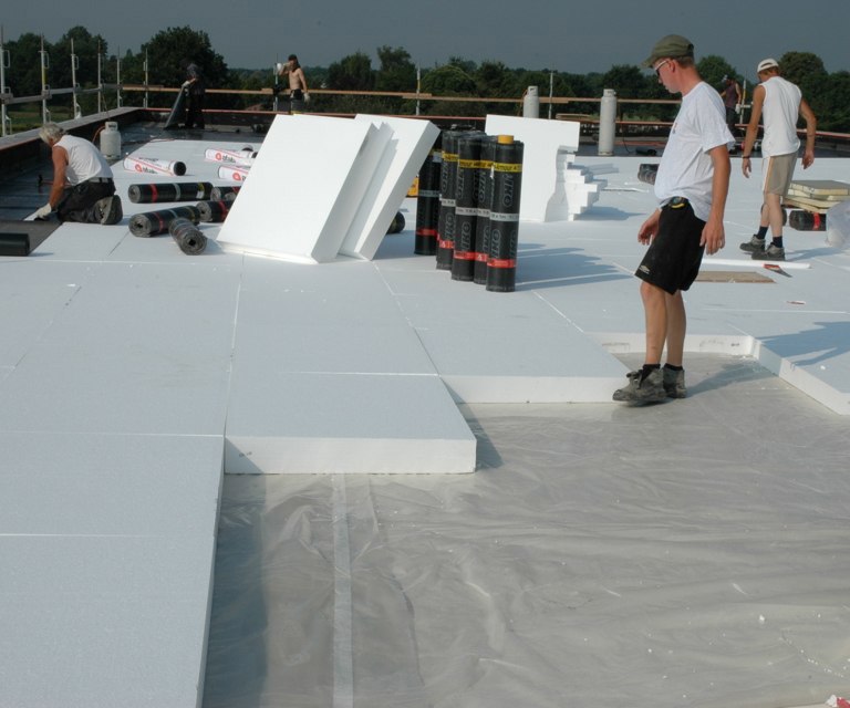 Projectfoto van verwerkers die plat dak EPS-SE isolatieplaten plaatsen op een werk. 